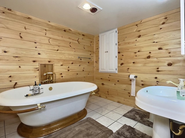 bathroom with tile patterned floors, a bathtub, wood walls, and sink