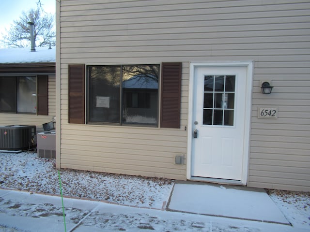 snow covered property entrance featuring central AC unit