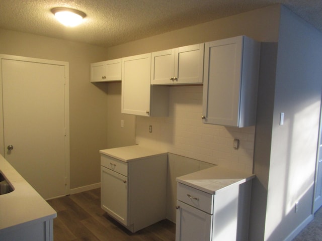 kitchen with decorative backsplash, white cabinets, dark wood-type flooring, and a textured ceiling