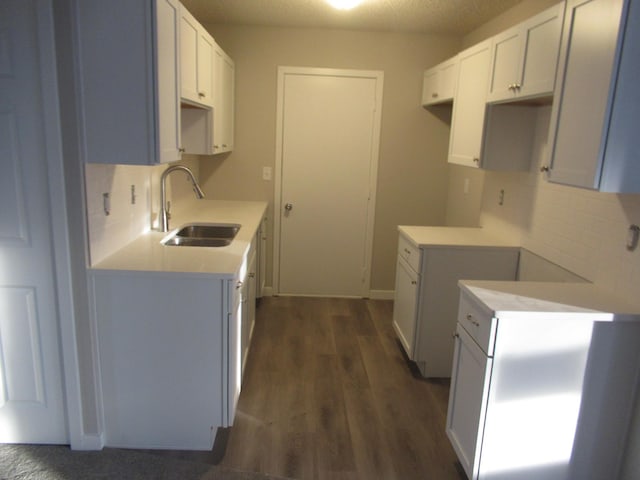 kitchen with a textured ceiling, dark hardwood / wood-style floors, white cabinetry, and sink