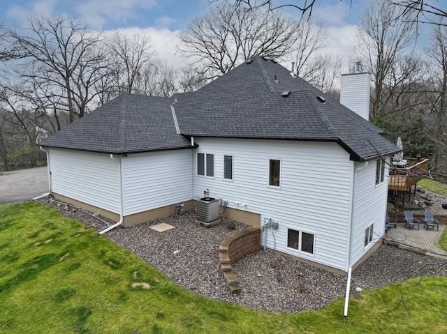 back of house with central AC unit and a lawn