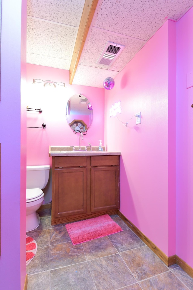 bathroom with toilet, beam ceiling, vanity, and tile patterned floors