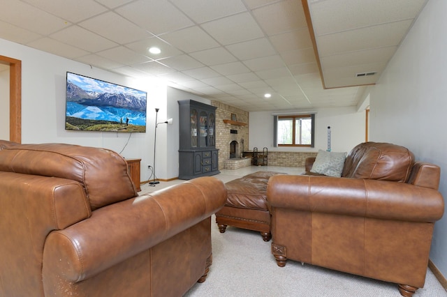 carpeted living room with a wood stove and a drop ceiling