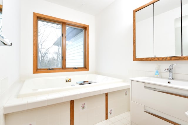 bathroom with tile patterned flooring, vanity, and tiled bath