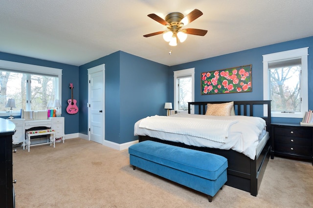 bedroom featuring ceiling fan, light colored carpet, and multiple windows