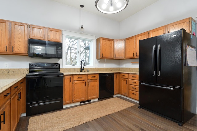 kitchen featuring light stone countertops, sink, dark hardwood / wood-style floors, pendant lighting, and black appliances