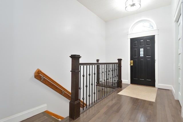 foyer with dark wood-type flooring and vaulted ceiling