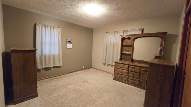 unfurnished bedroom featuring light carpet and a textured ceiling