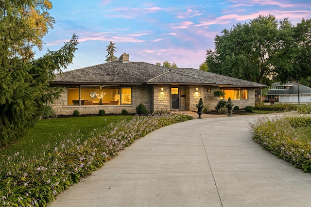 single story home with a front yard, stone siding, and a chimney