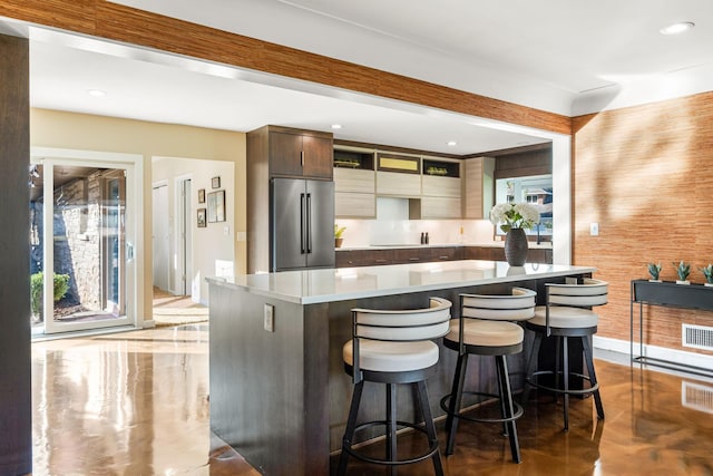 kitchen with high quality fridge, light countertops, a kitchen bar, modern cabinets, and a center island