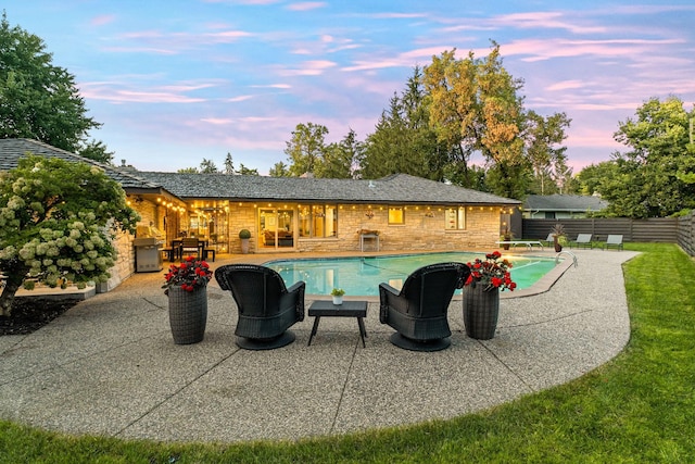 pool at dusk with a fenced in pool, fence, grilling area, and a patio area