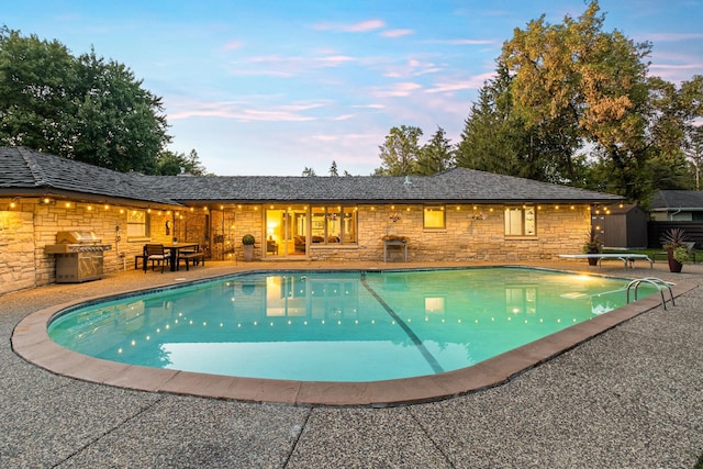 pool featuring a patio, area for grilling, a diving board, and an outdoor structure