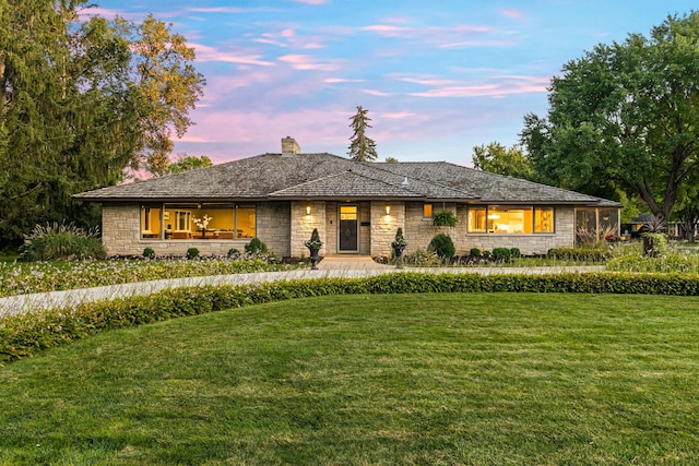 view of front facade featuring stone siding, a chimney, and a front lawn