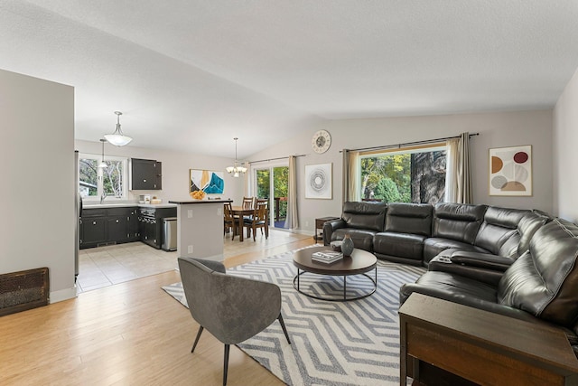 living room with a chandelier, light wood-type flooring, and vaulted ceiling