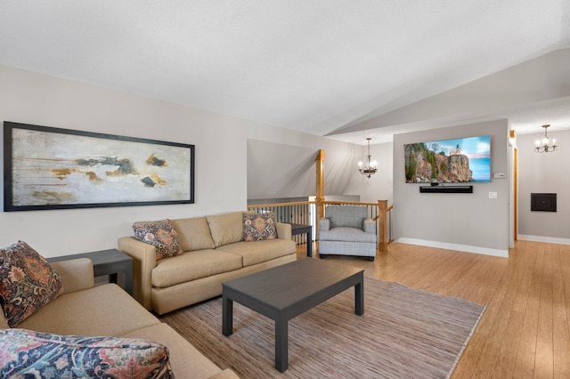 living room featuring vaulted ceiling, a chandelier, and light hardwood / wood-style floors