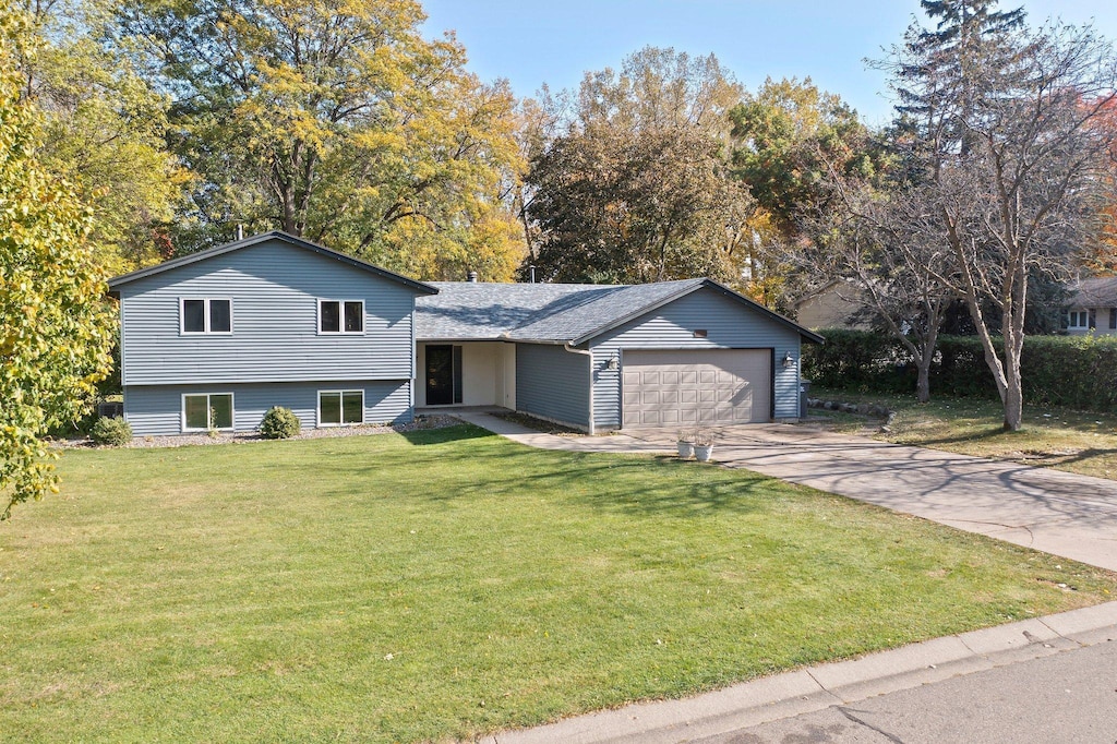 split level home featuring a garage and a front lawn