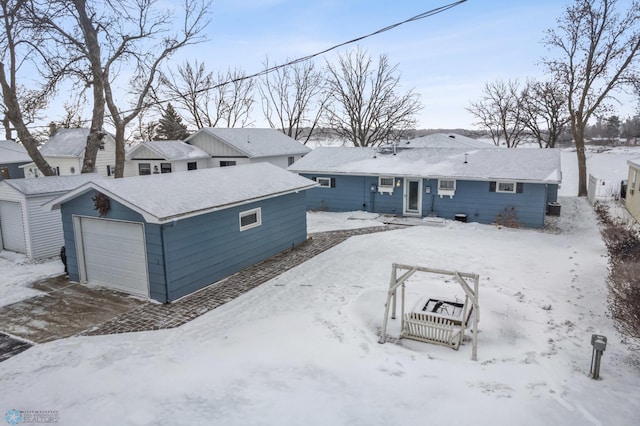 snow covered rear of property featuring a garage