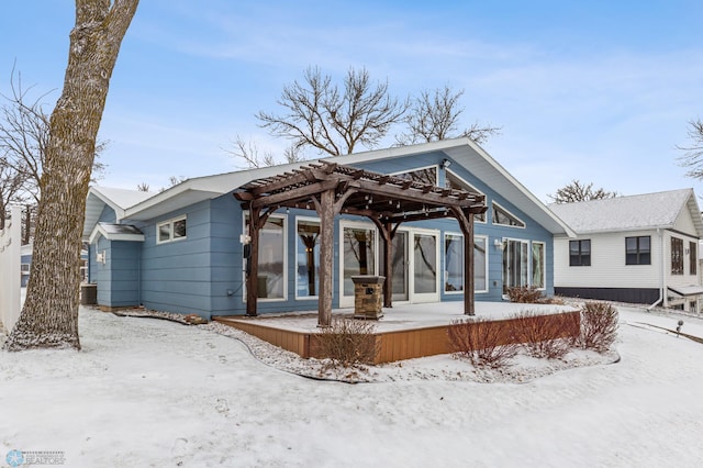 snow covered back of property featuring central AC unit and a pergola