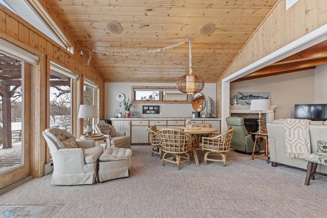 dining area with carpet flooring, wood ceiling, a stone fireplace, lofted ceiling, and wood walls