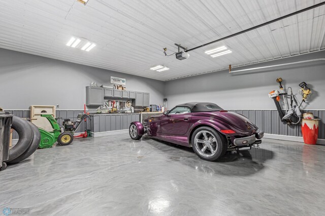 garage featuring a garage door opener and wooden walls