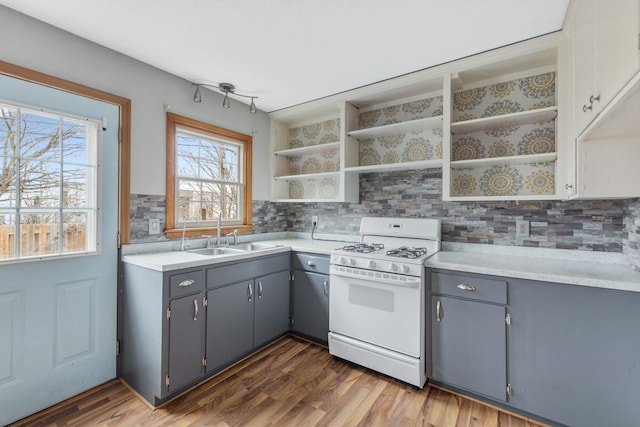 kitchen featuring decorative backsplash, gray cabinetry, dark wood-type flooring, sink, and white gas stove