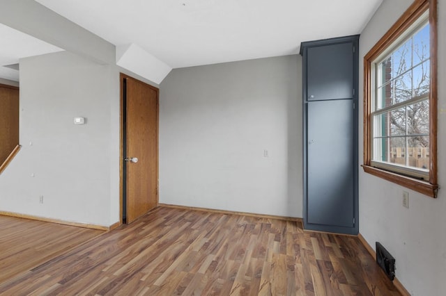 unfurnished bedroom featuring vaulted ceiling, dark hardwood / wood-style flooring, and multiple windows