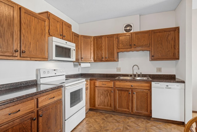 kitchen featuring sink, white appliances, a textured ceiling, and light parquet flooring