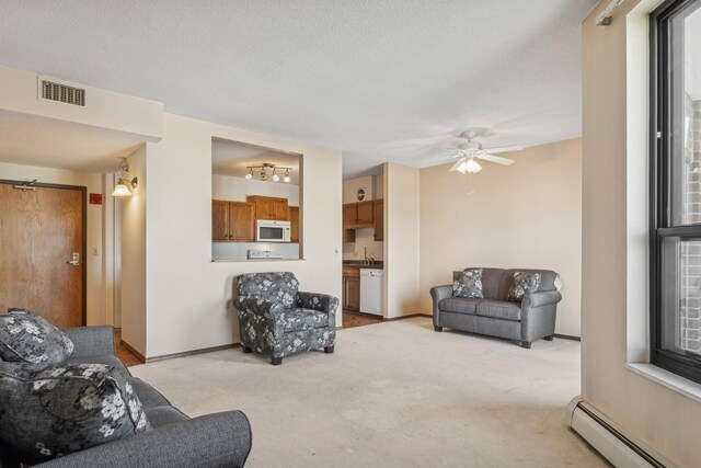 carpeted living room featuring ceiling fan, a baseboard heating unit, sink, and a textured ceiling