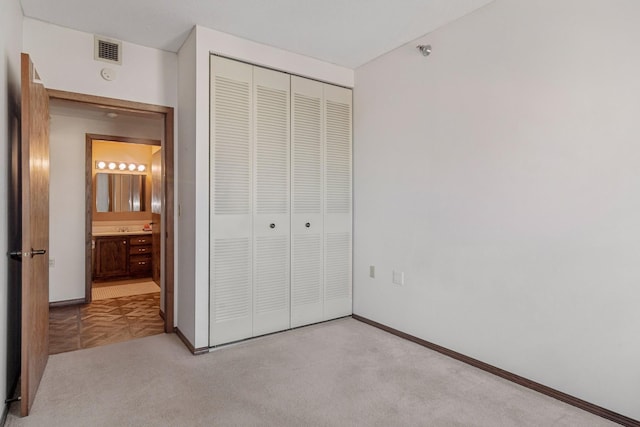 unfurnished bedroom featuring light colored carpet and a closet