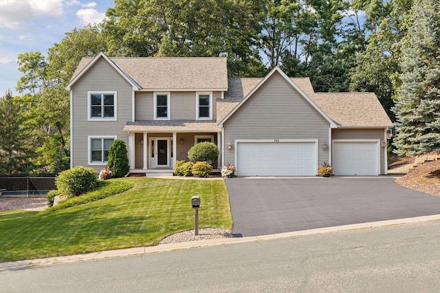 traditional home with driveway, a front lawn, a garage, and roof with shingles