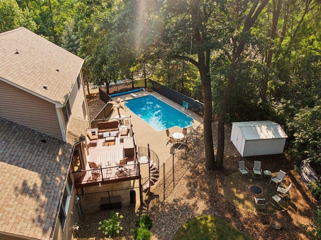 view of swimming pool featuring a fenced in pool, a patio area, a storage shed, a deck, and an outbuilding