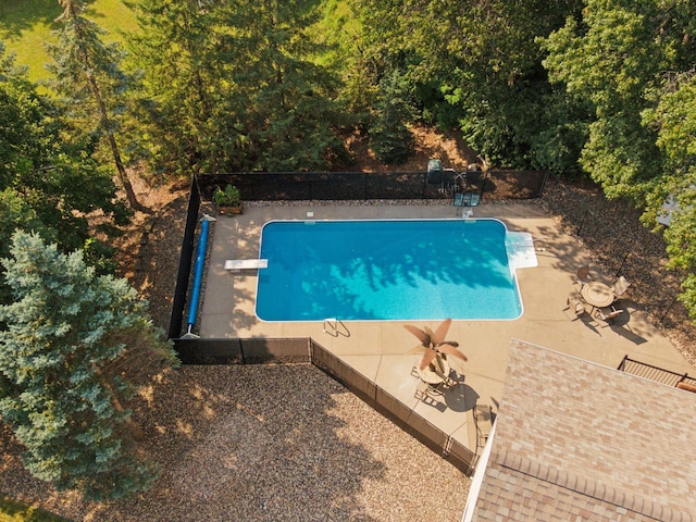 view of pool featuring a patio area, a fenced in pool, fence, and a diving board