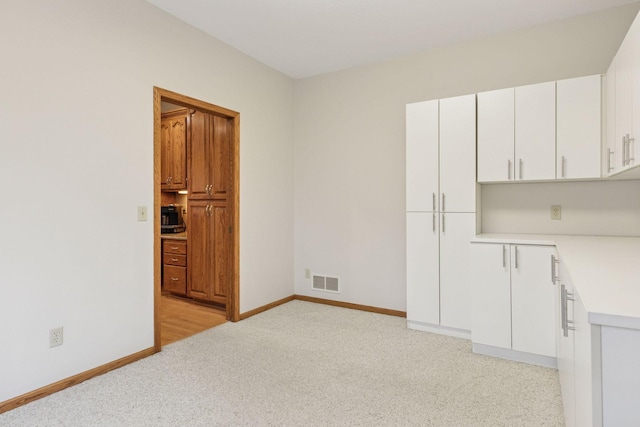 spare room featuring visible vents, light colored carpet, and baseboards