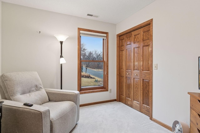 living area featuring light carpet, visible vents, a textured ceiling, and baseboards