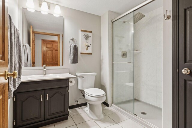 full bath featuring toilet, a stall shower, tile patterned flooring, baseboards, and vanity