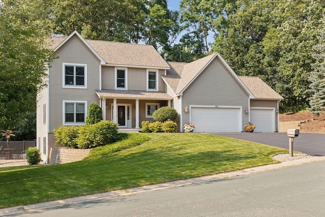 view of front of property with a front lawn, fence, roof with shingles, a garage, and driveway