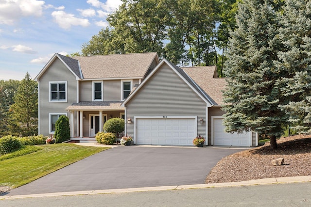 traditional home with a front lawn, an attached garage, driveway, and a shingled roof