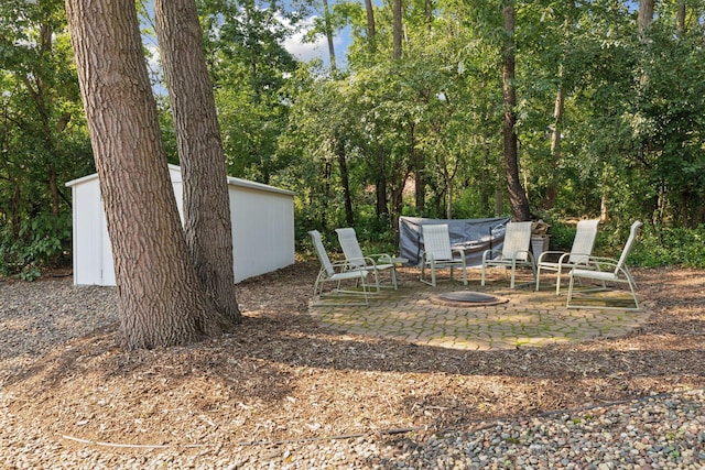 view of yard featuring an outdoor fire pit, a patio, and an outdoor structure