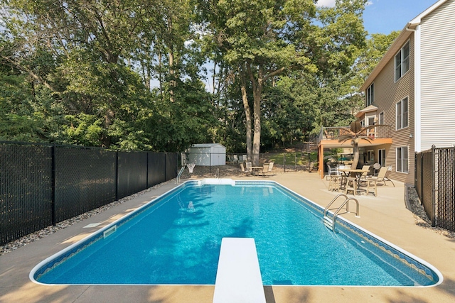 view of pool with a patio, a fenced backyard, and a diving board