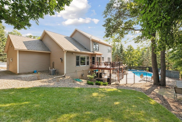 back of property with a lawn, fence, a wooden deck, a fenced in pool, and stairs