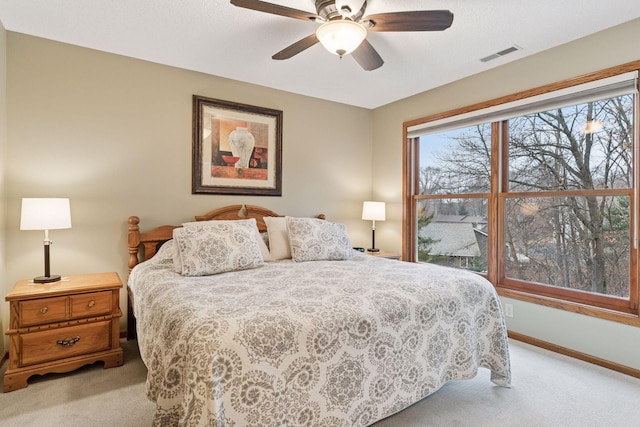 bedroom featuring light carpet, visible vents, a ceiling fan, and baseboards