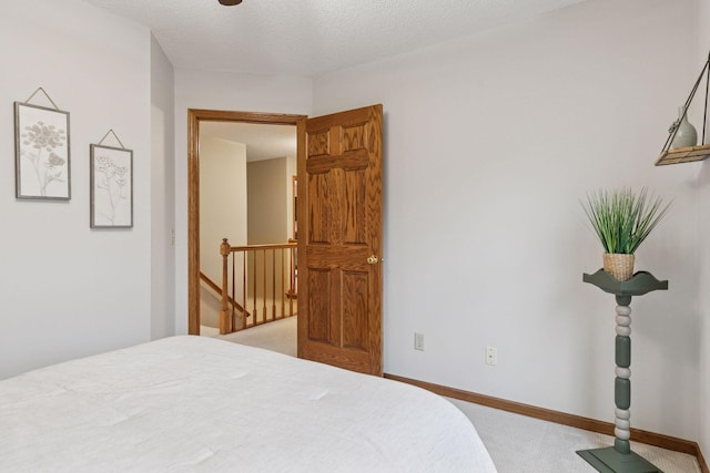 bedroom featuring light colored carpet, a textured ceiling, and baseboards