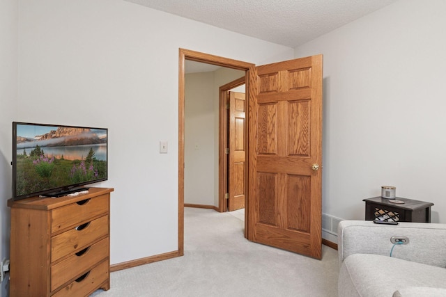 sitting room featuring a textured ceiling, baseboards, and light carpet