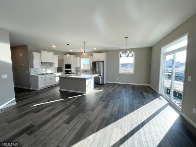 kitchen with white cabinets, appliances with stainless steel finishes, decorative light fixtures, and a kitchen island