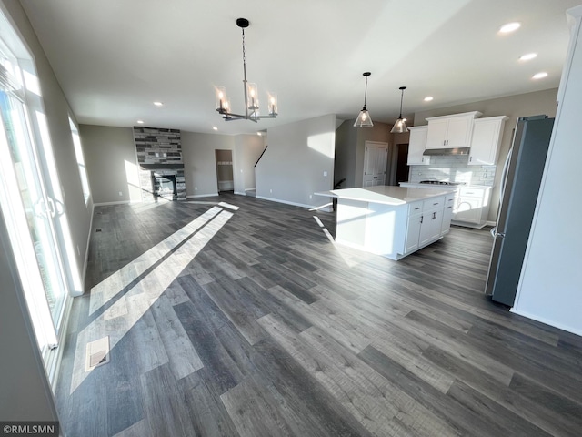 kitchen with stainless steel appliances, a kitchen island, decorative light fixtures, dark hardwood / wood-style floors, and white cabinetry