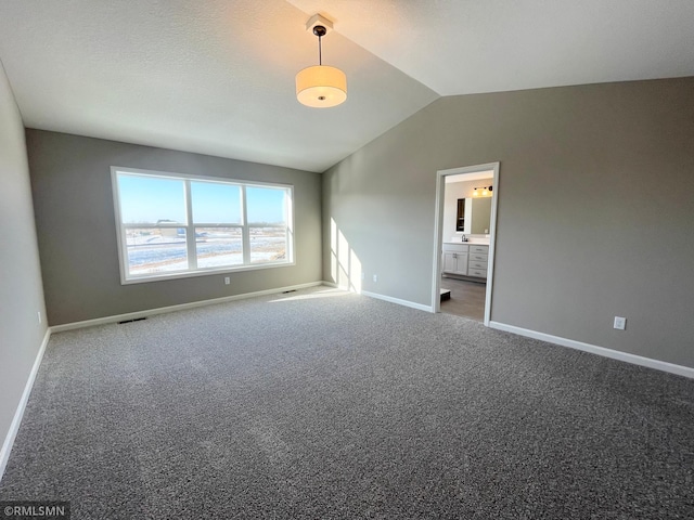 spare room with dark carpet and vaulted ceiling