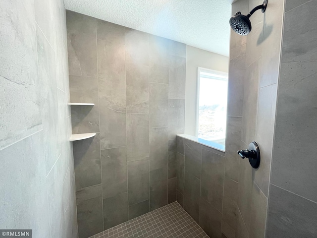 bathroom with a textured ceiling and tiled shower