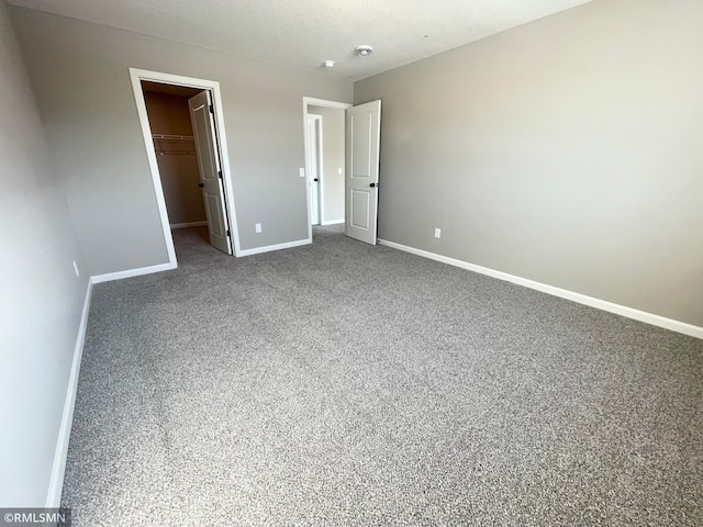 unfurnished bedroom with a walk in closet, carpet floors, and a closet