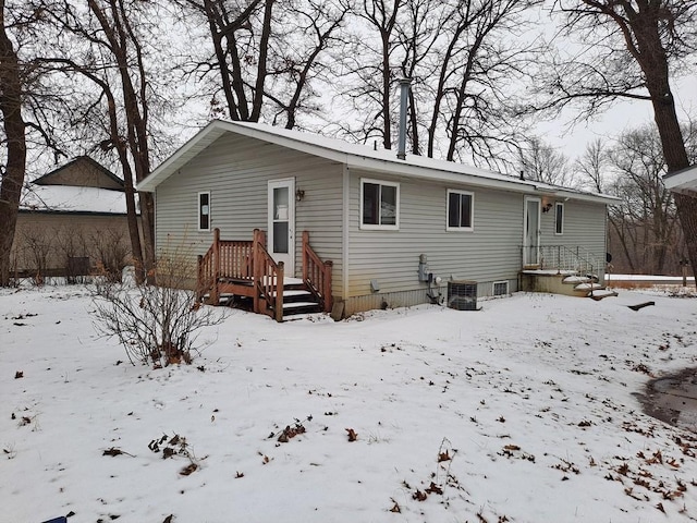 snow covered back of property with central AC