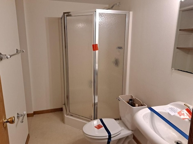 bathroom with sink, a shower with shower door, and toilet